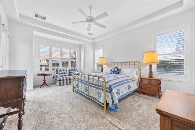 bedroom with ceiling fan, carpet flooring, and a raised ceiling