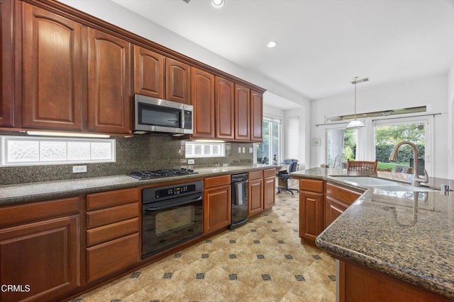 kitchen with decorative light fixtures, sink, backsplash, dark stone counters, and stainless steel appliances