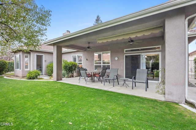 back of house featuring a lawn, ceiling fan, and a patio area