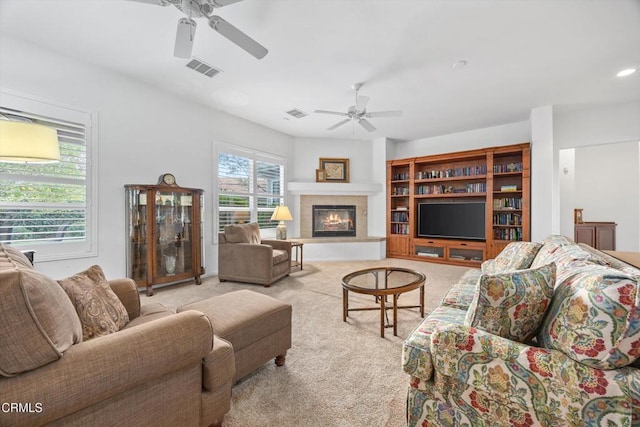 carpeted living room featuring a tiled fireplace and ceiling fan