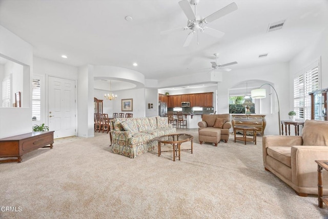 carpeted living room with ceiling fan with notable chandelier