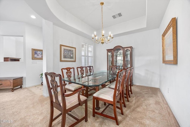 carpeted dining area with a notable chandelier and a tray ceiling