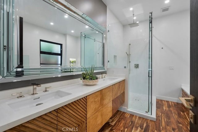 bathroom featuring a stall shower, visible vents, a sink, and wood finished floors