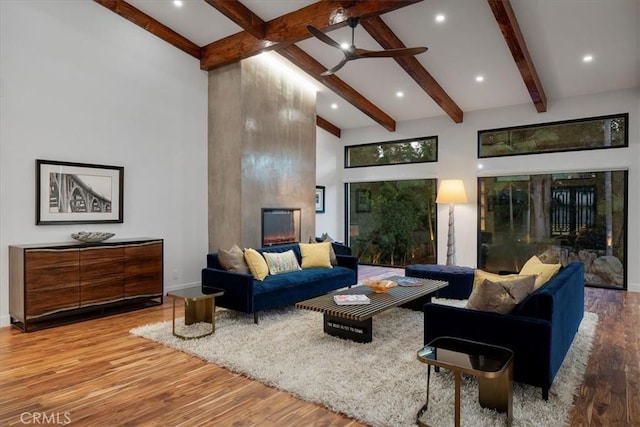 living area with a ceiling fan, wood finished floors, high vaulted ceiling, beamed ceiling, and baseboards