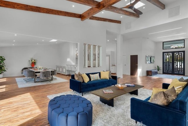 living area featuring recessed lighting, wood finished floors, a towering ceiling, visible vents, and beamed ceiling