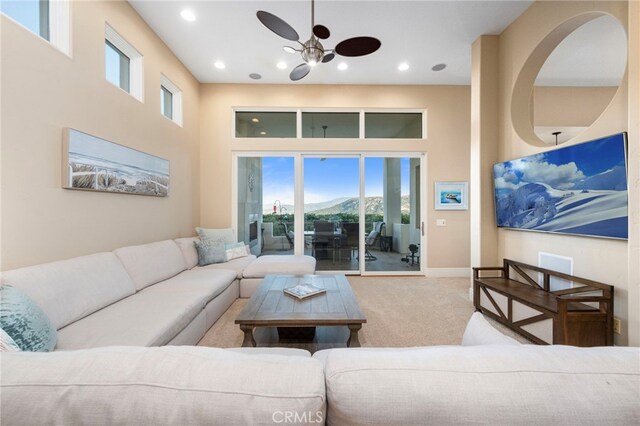 living room featuring a ceiling fan, a high ceiling, carpet floors, baseboards, and recessed lighting