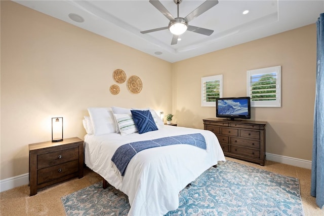 carpeted bedroom with baseboards, a tray ceiling, recessed lighting, and ceiling fan