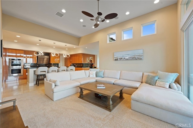 living room with recessed lighting, visible vents, a ceiling fan, and a towering ceiling