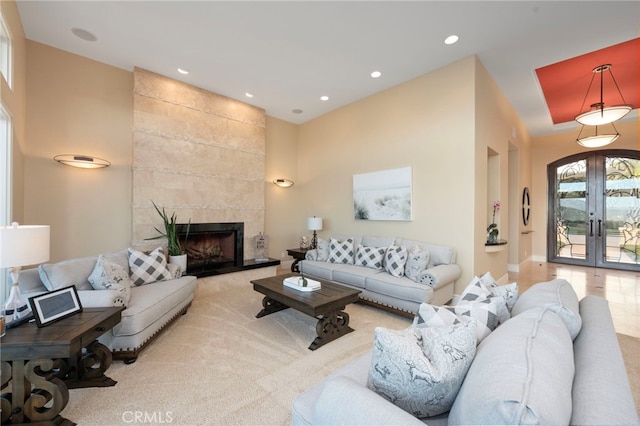 carpeted living room with recessed lighting, a tile fireplace, and french doors