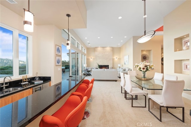 dining room with light colored carpet, a healthy amount of sunlight, a large fireplace, and recessed lighting