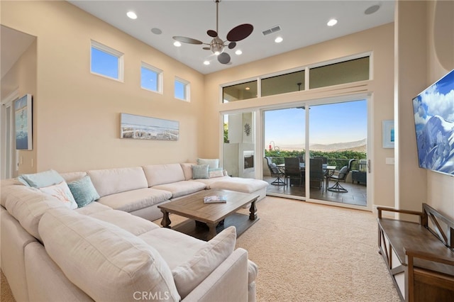 carpeted living room featuring recessed lighting, visible vents, and a towering ceiling
