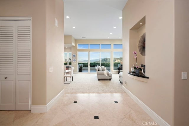 corridor with recessed lighting, carpet, tile patterned floors, a mountain view, and baseboards