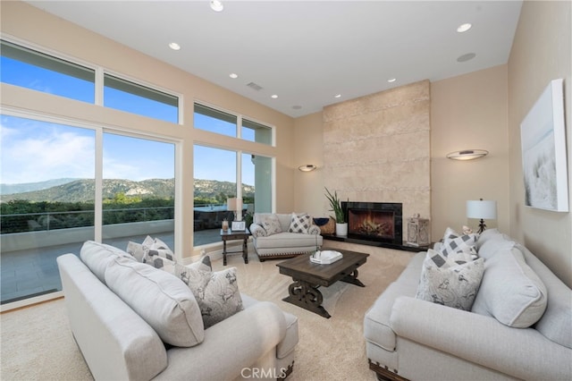 living room featuring a mountain view, visible vents, recessed lighting, a high ceiling, and a fireplace