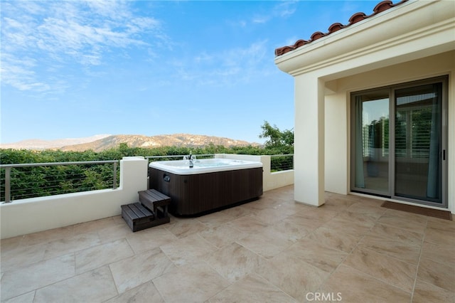 view of patio featuring a hot tub and a mountain view