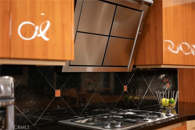kitchen with stainless steel gas stovetop, dark countertops, decorative backsplash, and brown cabinetry