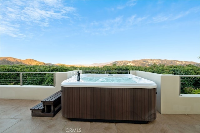 view of patio with a hot tub and a mountain view