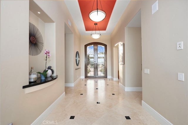 entryway featuring baseboards, french doors, visible vents, and a tray ceiling