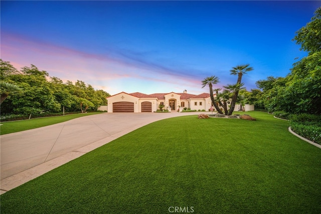 mediterranean / spanish-style home with stucco siding, a front lawn, an attached garage, and curved driveway