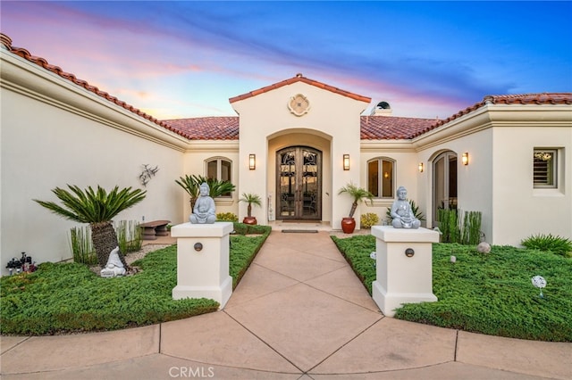 mediterranean / spanish house with french doors, a tiled roof, and stucco siding