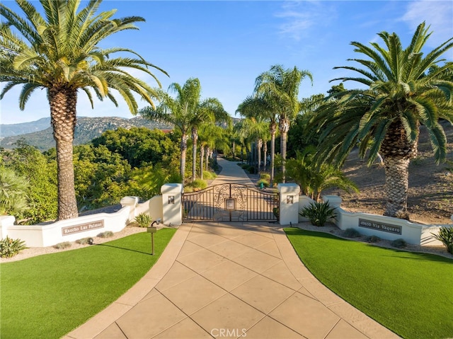 view of gate featuring a lawn, fence, and a mountain view