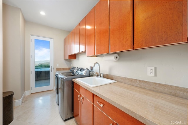 washroom with washer and clothes dryer, a sink, light tile patterned floors, cabinet space, and baseboards