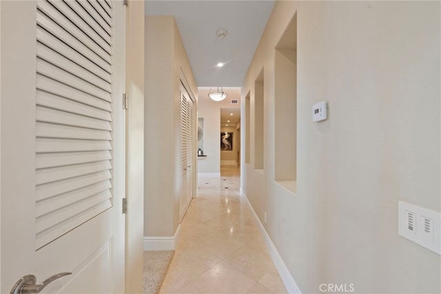 hallway with light tile patterned flooring and baseboards