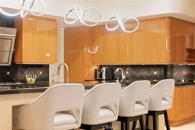 kitchen with a kitchen bar, decorative backsplash, modern cabinets, and dark countertops