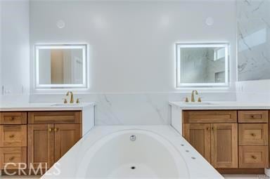 full bathroom with a bathtub, two vanities, and a sink