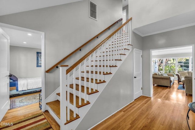 stairs with crown molding and wood-type flooring