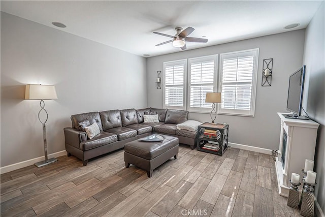 living area with a ceiling fan, baseboards, and wood finished floors