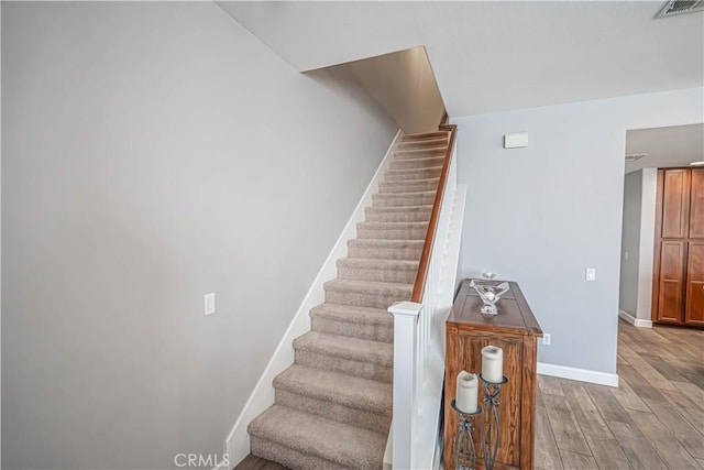 stairs featuring baseboards, visible vents, and wood finished floors