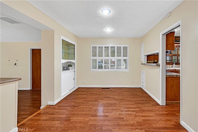 unfurnished dining area featuring sink, hardwood / wood-style floors, and a textured ceiling