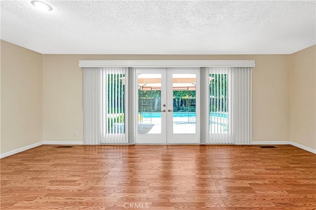 empty room featuring french doors, a wealth of natural light, and light wood-type flooring