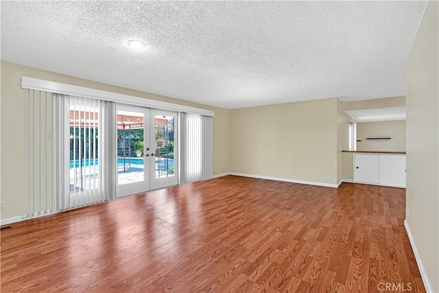 empty room featuring french doors, a textured ceiling, and hardwood / wood-style flooring