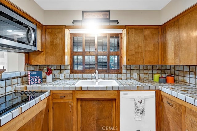 kitchen featuring sink, tasteful backsplash, tile countertops, black electric cooktop, and white dishwasher