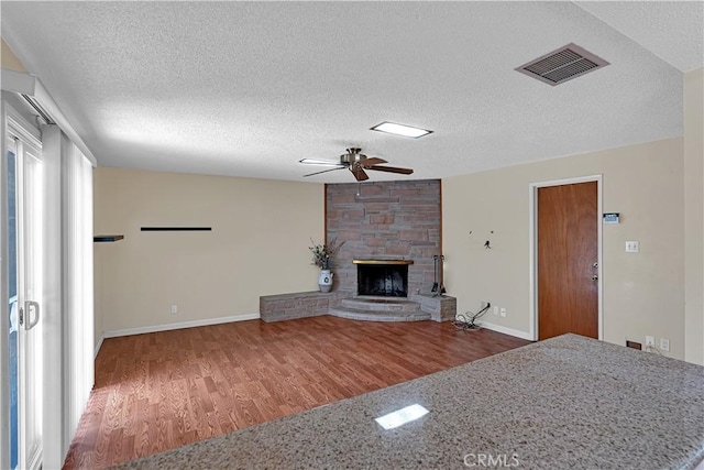 unfurnished living room with hardwood / wood-style flooring, ceiling fan, a textured ceiling, and a fireplace