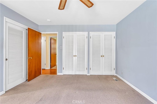 unfurnished bedroom with multiple closets, light colored carpet, and ceiling fan