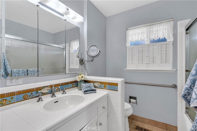 full bathroom with tile patterned flooring, enclosed tub / shower combo, vanity, toilet, and a healthy amount of sunlight