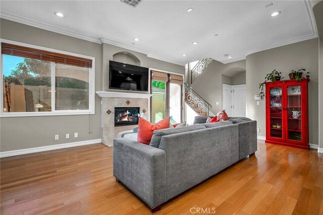 living room featuring hardwood / wood-style flooring, ornamental molding, and a fireplace