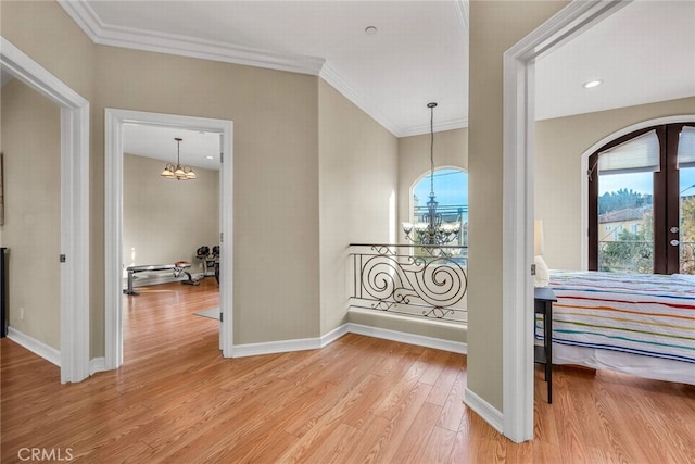 corridor featuring an inviting chandelier, ornamental molding, light hardwood / wood-style floors, and french doors