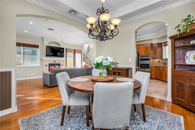 dining area featuring an inviting chandelier, ornamental molding, and light hardwood / wood-style floors