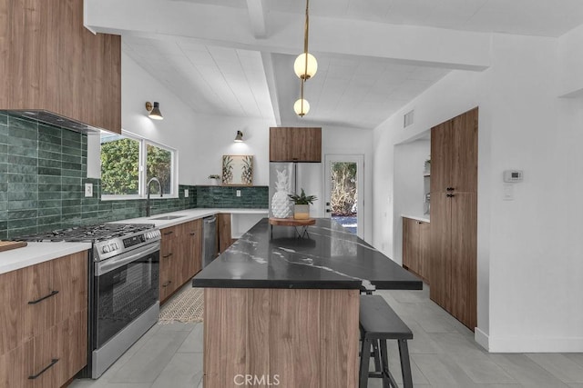 kitchen with stainless steel gas range oven, decorative backsplash, a breakfast bar area, and modern cabinets