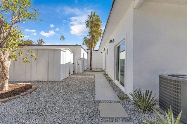 view of home's exterior with stucco siding, an outdoor structure, central AC, and fence