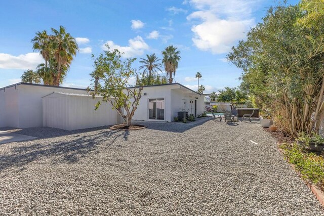 back of house with stucco siding, central AC, and fence