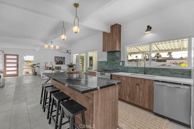 kitchen with brown cabinetry, beam ceiling, appliances with stainless steel finishes, a kitchen bar, and tasteful backsplash