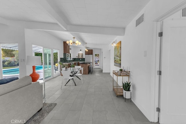 living area featuring beam ceiling, visible vents, and a notable chandelier