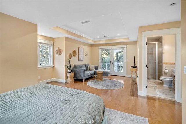 bedroom with access to exterior, visible vents, a tray ceiling, and wood finished floors