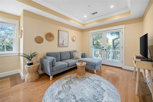 living room with light wood-style flooring, baseboards, a raised ceiling, and french doors