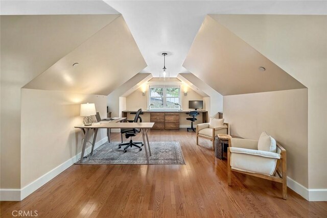 home office featuring vaulted ceiling, wood finished floors, and baseboards