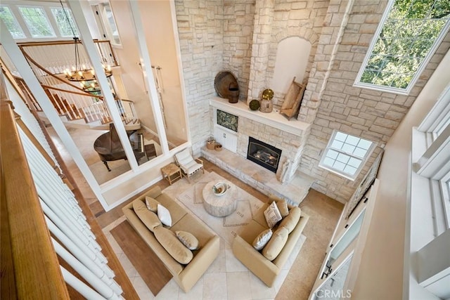 living room with a wealth of natural light, a notable chandelier, and a stone fireplace